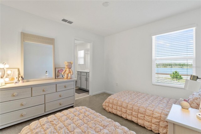 bedroom with baseboards, visible vents, carpet floors, and connected bathroom