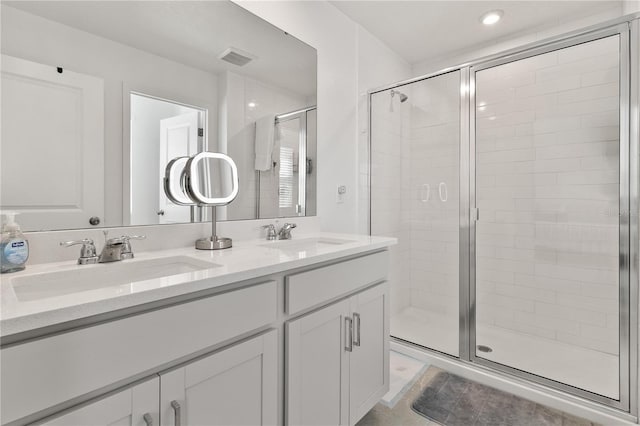 full bath with double vanity, a stall shower, and a sink