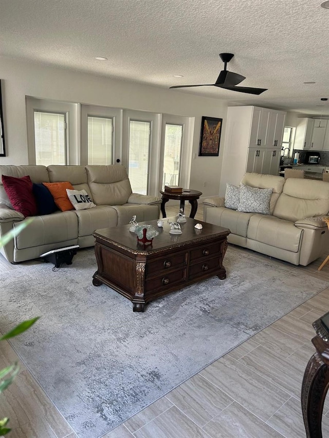 living room with a textured ceiling, a ceiling fan, and a wealth of natural light