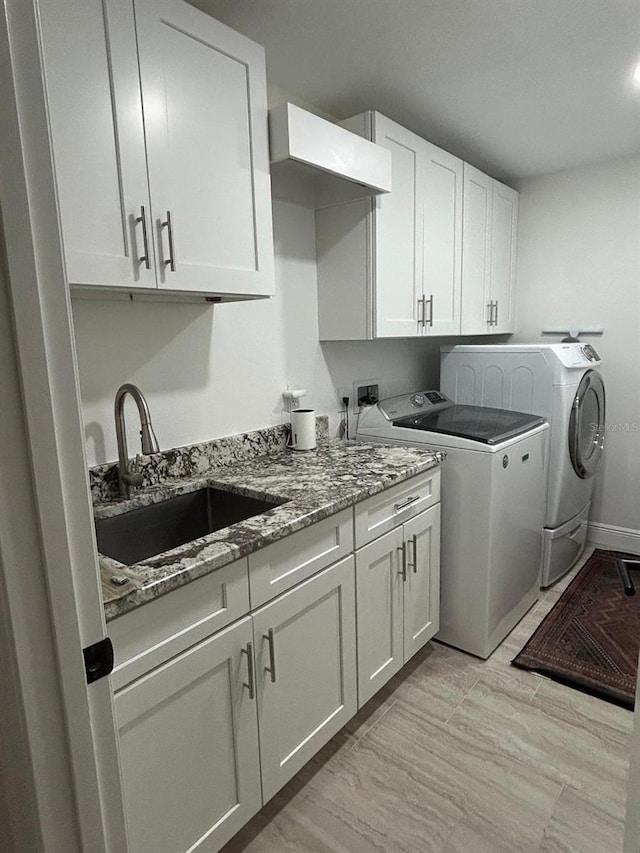 washroom with washing machine and dryer, a sink, and cabinet space