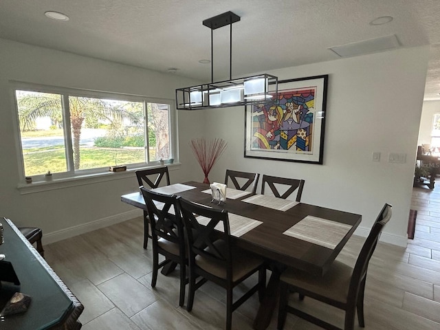 dining area featuring a textured ceiling, baseboards, and wood finished floors