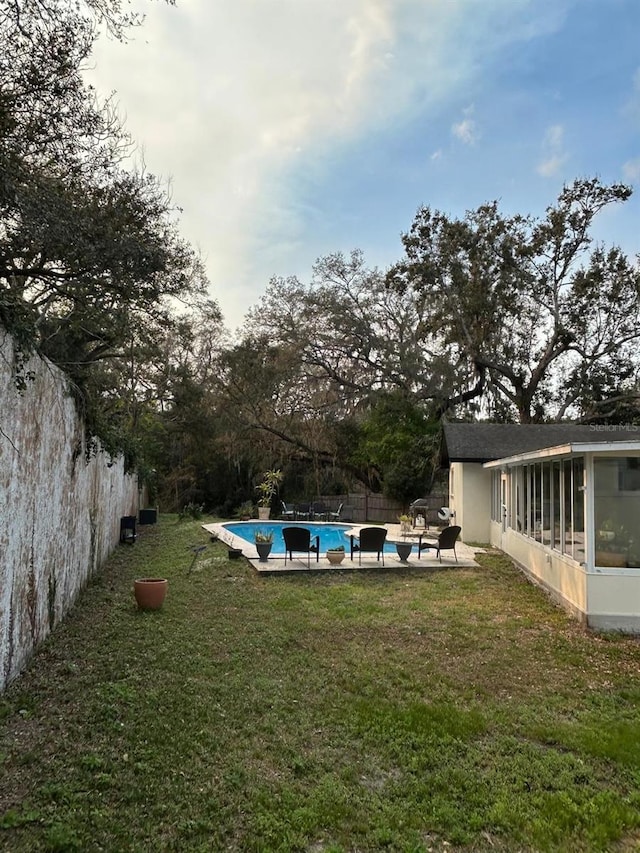 view of yard featuring a sunroom, a fenced backyard, a patio area, and a fenced in pool