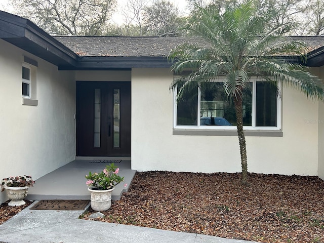 doorway to property featuring a shingled roof and stucco siding