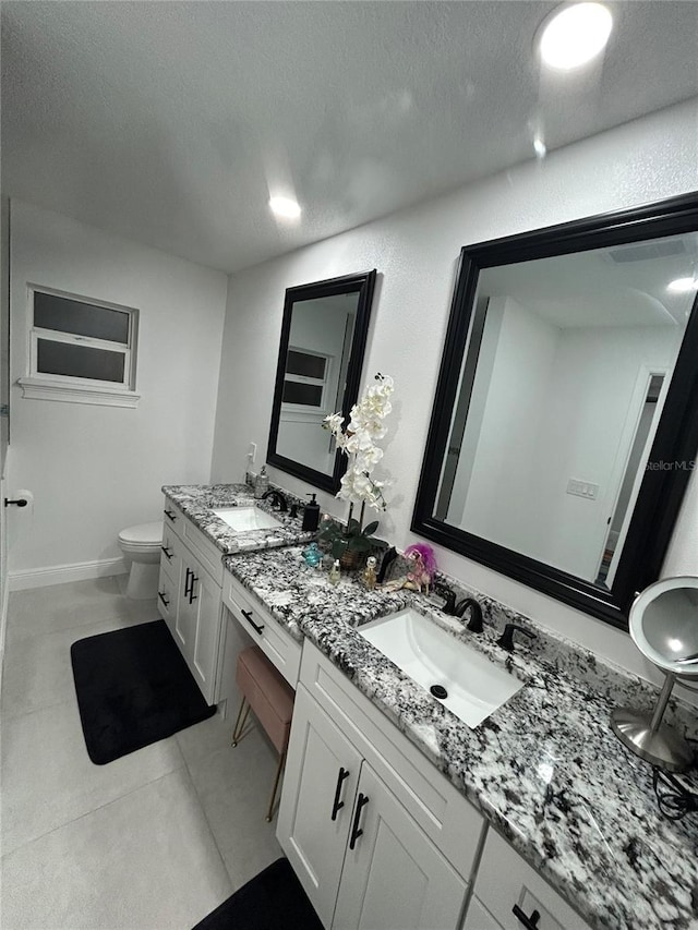 full bathroom featuring toilet, a textured ceiling, vanity, baseboards, and tile patterned floors