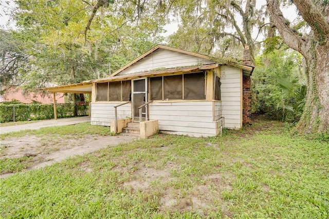 view of front of house with driveway, a sunroom, fence, and a carport