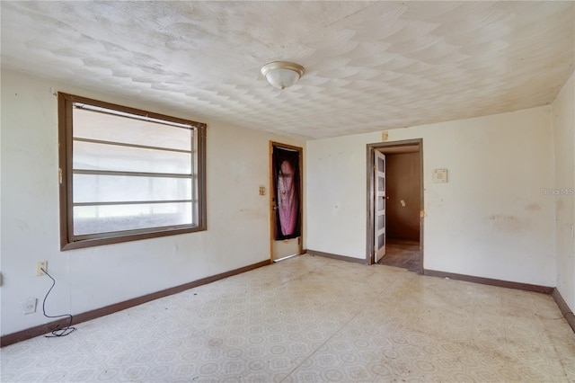 unfurnished room with a textured ceiling and baseboards