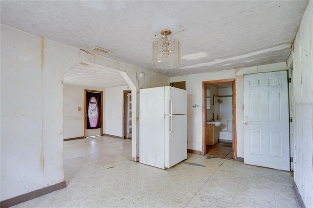 interior space with arched walkways, visible vents, baseboards, freestanding refrigerator, and light floors