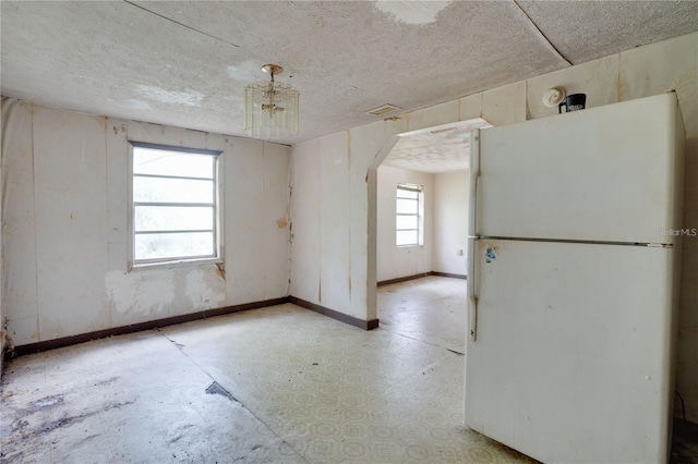 unfurnished room with baseboards, arched walkways, and a textured ceiling