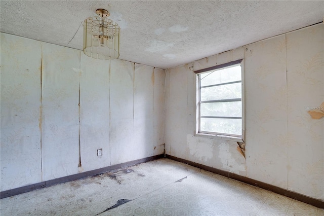 empty room featuring a textured ceiling, baseboards, and tile patterned floors