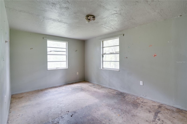 unfurnished room with a wealth of natural light, unfinished concrete flooring, and a textured ceiling