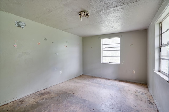 empty room featuring a textured ceiling and unfinished concrete floors