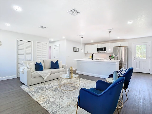 living area with dark wood-type flooring, recessed lighting, visible vents, and baseboards