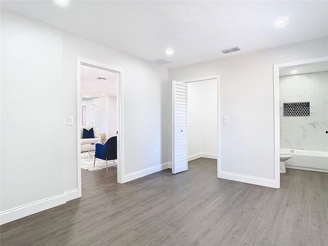 unfurnished bedroom with a closet, wood finished floors, visible vents, and baseboards