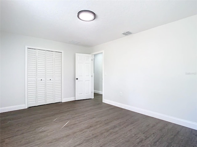 unfurnished bedroom with dark wood-type flooring, visible vents, and baseboards