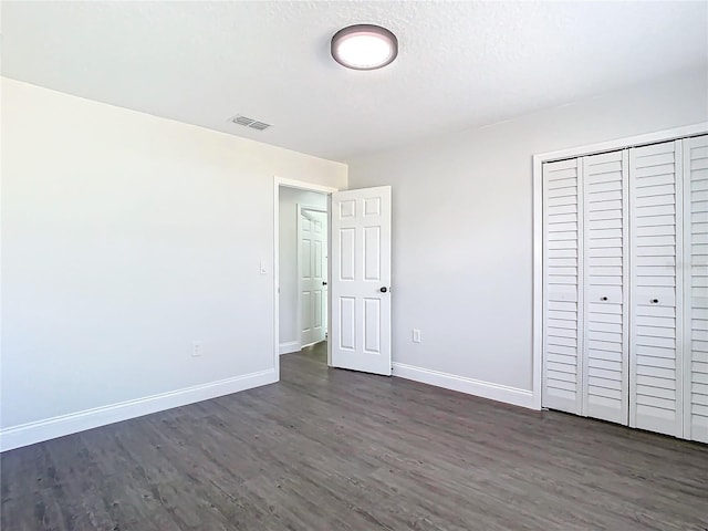 unfurnished bedroom featuring baseboards, visible vents, and dark wood finished floors