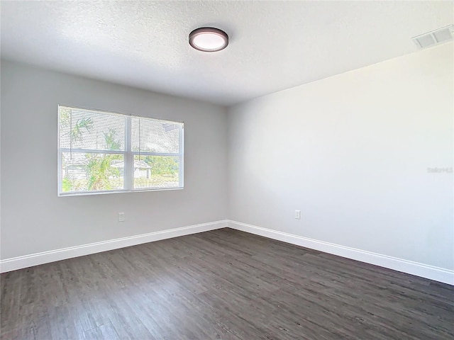 unfurnished room with dark wood-type flooring, visible vents, a textured ceiling, and baseboards