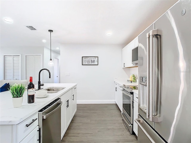 kitchen featuring stainless steel appliances, visible vents, white cabinets, a sink, and wood finished floors