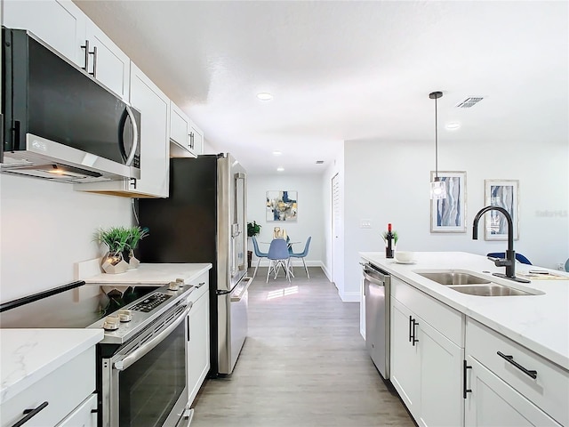 kitchen with pendant lighting, stainless steel appliances, visible vents, white cabinets, and a sink