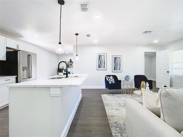 kitchen with visible vents, a sink, stainless steel refrigerator with ice dispenser, and baseboards