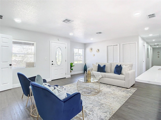 living room with wood finished floors, visible vents, and baseboards