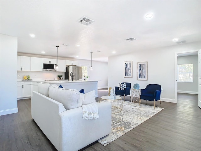 living area with dark wood-style flooring and visible vents