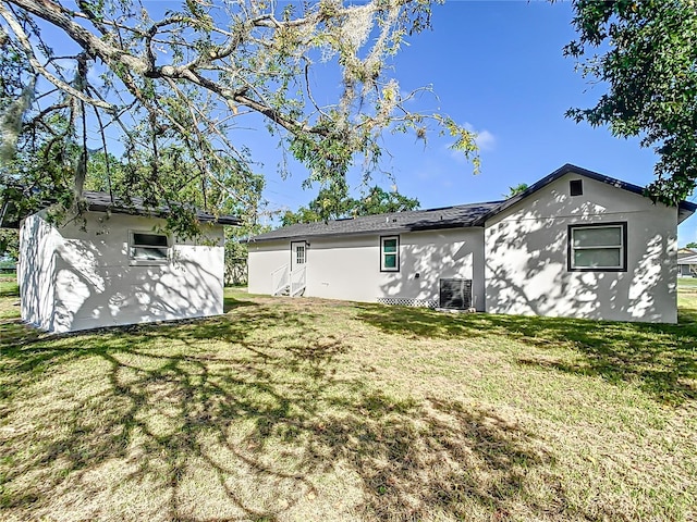 back of house with a lawn and stucco siding