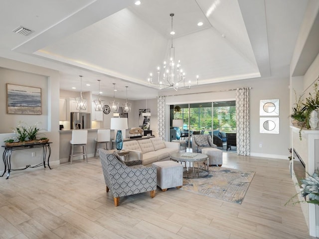 living area featuring light wood finished floors, a raised ceiling, visible vents, and a notable chandelier