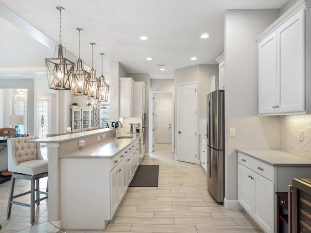 kitchen featuring white cabinets, a kitchen breakfast bar, decorative backsplash, and freestanding refrigerator