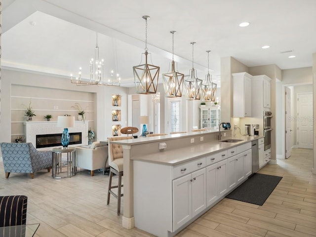 kitchen with a glass covered fireplace, appliances with stainless steel finishes, open floor plan, a kitchen bar, and a sink