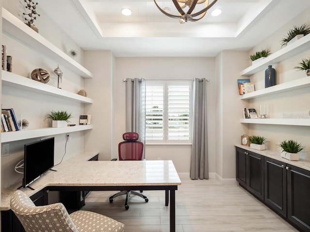 office space with a chandelier, a tray ceiling, baseboards, and light wood finished floors