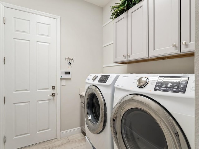 laundry room with light wood-type flooring, baseboards, cabinet space, and washing machine and clothes dryer