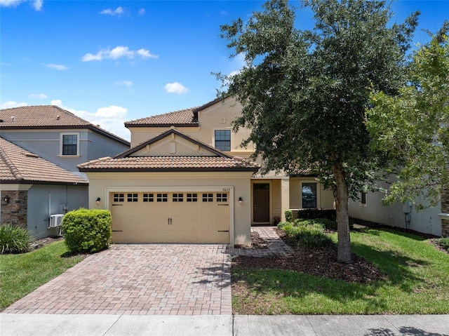 mediterranean / spanish house with a garage, decorative driveway, a tiled roof, and stucco siding