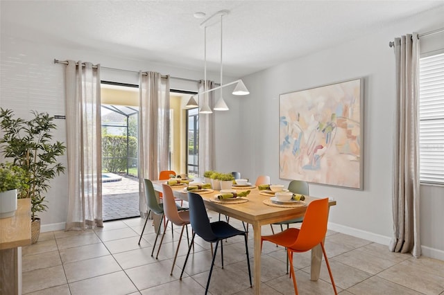 dining area with light tile patterned floors, a textured ceiling, and baseboards