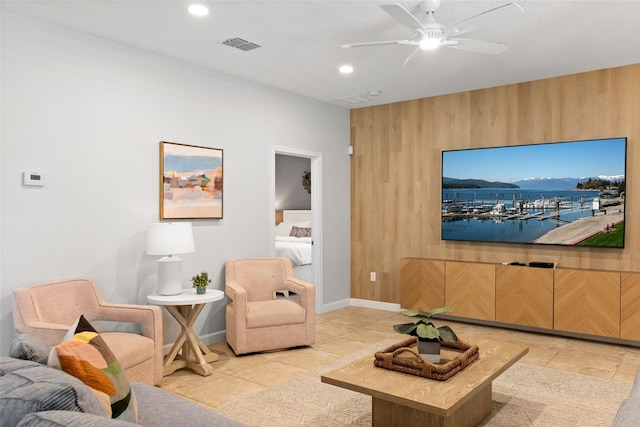 living room with baseboards, visible vents, a ceiling fan, wood walls, and recessed lighting