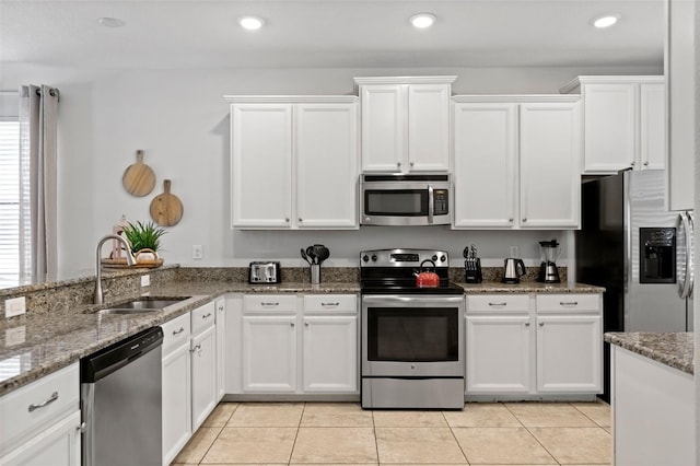 kitchen with appliances with stainless steel finishes, white cabinets, a sink, and light tile patterned flooring