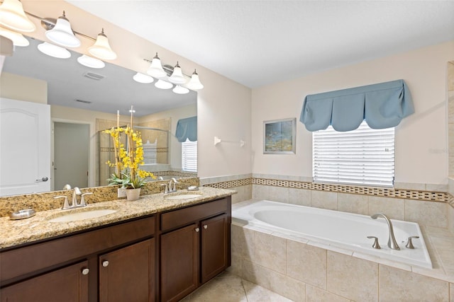 full bath featuring a stall shower, tile patterned flooring, a garden tub, and a sink