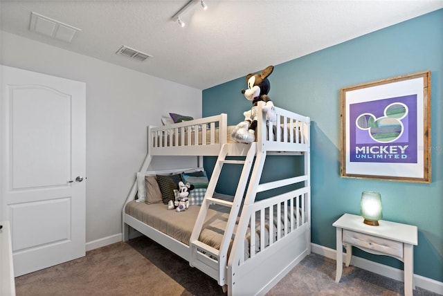 bedroom with rail lighting, carpet, visible vents, and baseboards