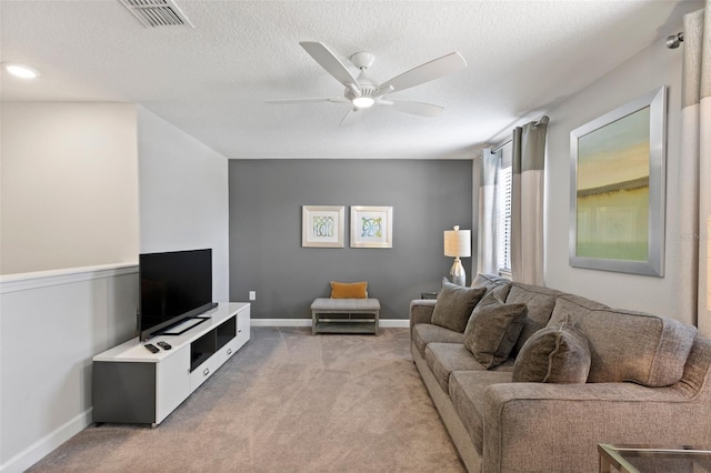 living room featuring a textured ceiling, light colored carpet, a ceiling fan, baseboards, and visible vents