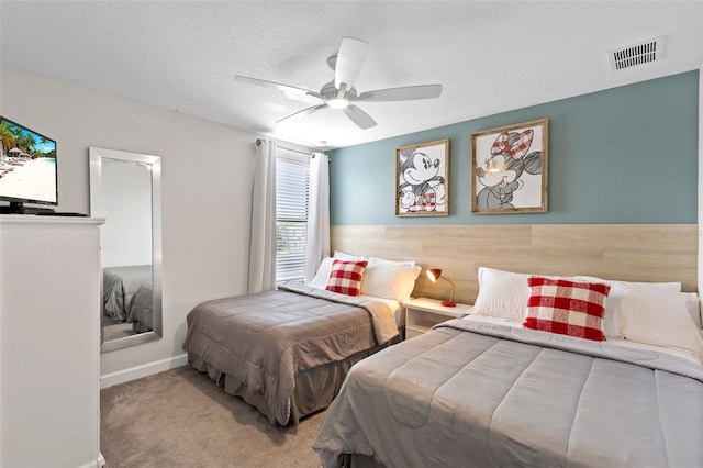 bedroom featuring carpet floors, a ceiling fan, visible vents, and a textured ceiling