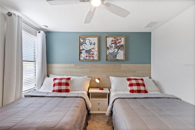 bedroom featuring carpet, visible vents, ceiling fan, and a textured ceiling