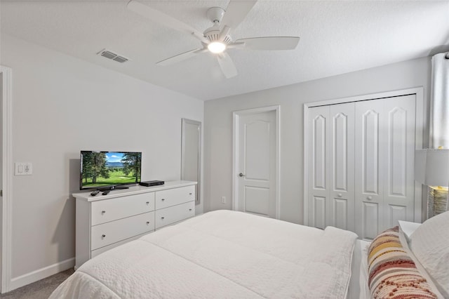 carpeted bedroom with a textured ceiling, a ceiling fan, visible vents, baseboards, and a closet