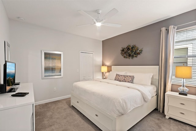 bedroom with a closet, light colored carpet, ceiling fan, and baseboards