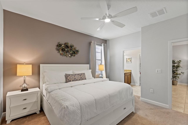 bedroom featuring light carpet, baseboards, visible vents, a ceiling fan, and connected bathroom