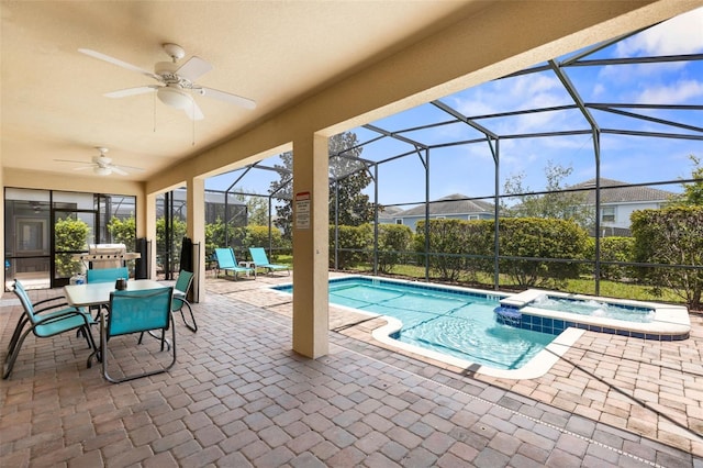 view of swimming pool featuring a pool with connected hot tub, glass enclosure, a patio area, and ceiling fan