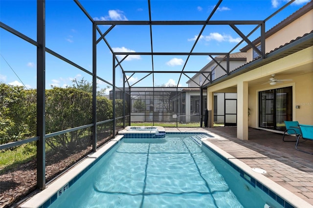 view of pool with glass enclosure, a pool with connected hot tub, a patio area, and a ceiling fan