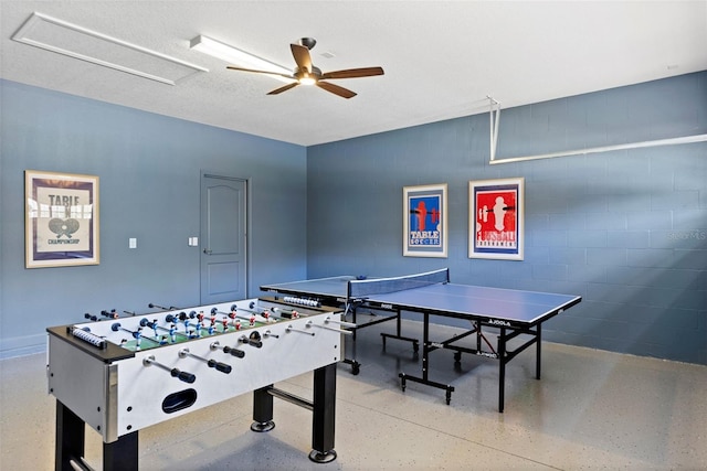 rec room with ceiling fan, speckled floor, and concrete block wall