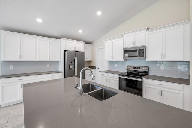 kitchen with appliances with stainless steel finishes, dark countertops, a sink, and white cabinetry