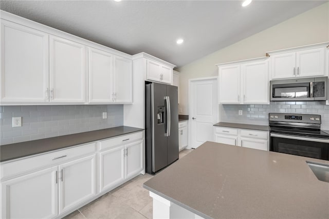 kitchen featuring lofted ceiling, dark countertops, white cabinetry, and appliances with stainless steel finishes