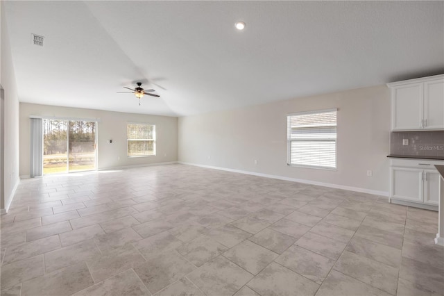 unfurnished living room featuring light tile patterned floors, baseboards, visible vents, ceiling fan, and vaulted ceiling