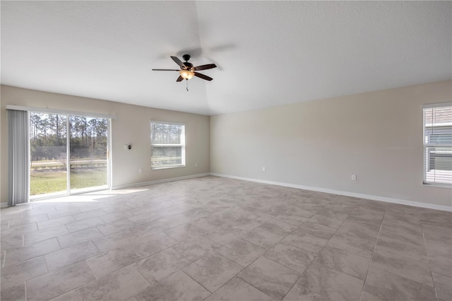 empty room featuring ceiling fan and baseboards